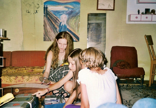 Three children gathered on the floor inside The Mute's House, looking through CDs beside a stereo. Drawings hang on the walls behind them, including a large copy of Edvard Munch's The Scream*, reflecting the creative atmosphere of the space
