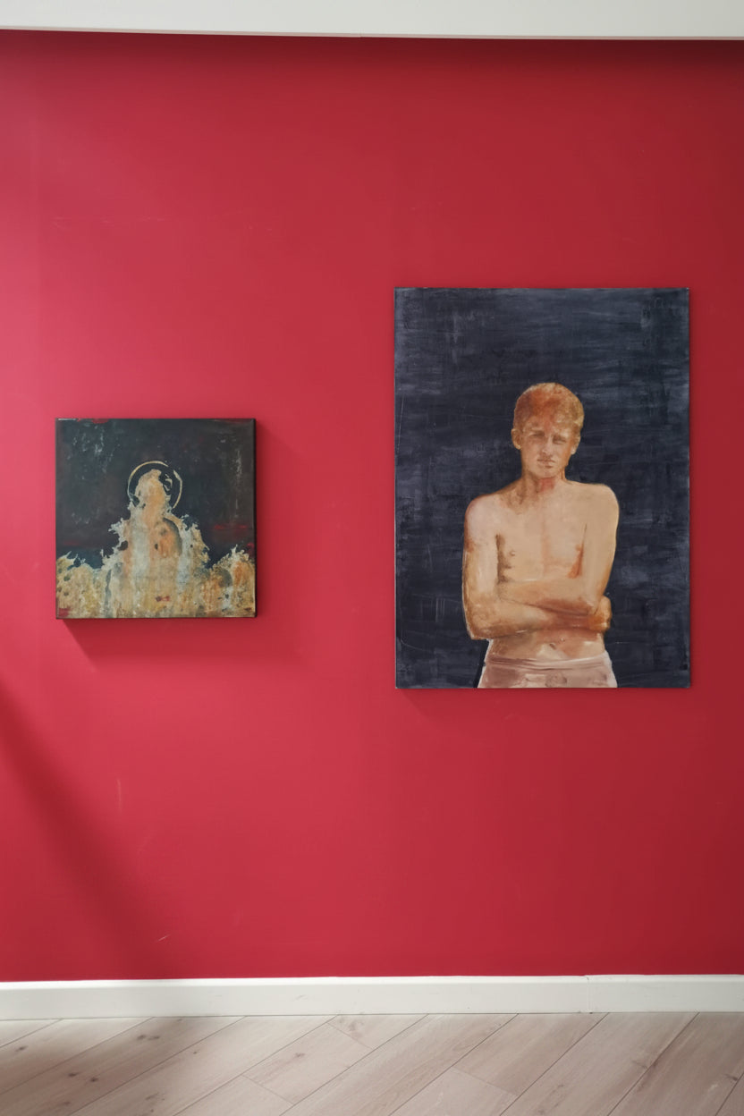 Two paintings on a red wall, one featuring a figure with a halo and the other showing a young boy figure.