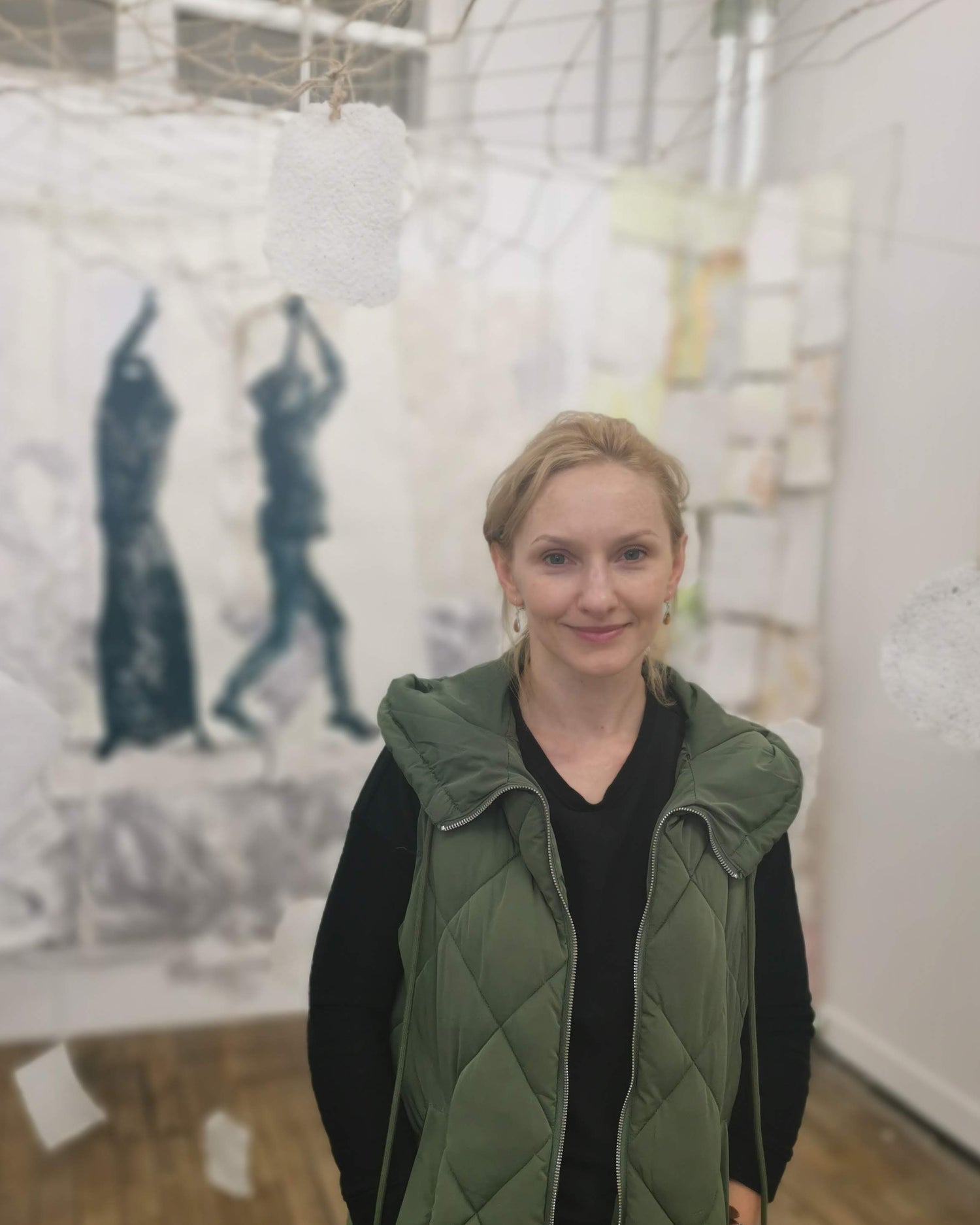 Woman standing in an art gallery with artwork on the walls. Artist Paulina Pawlik