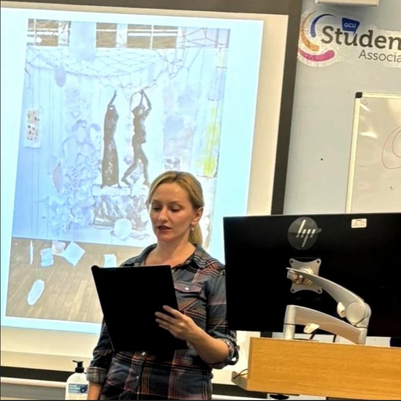 Woman giving a presentation in front of a screen with 'Student Association' branding.